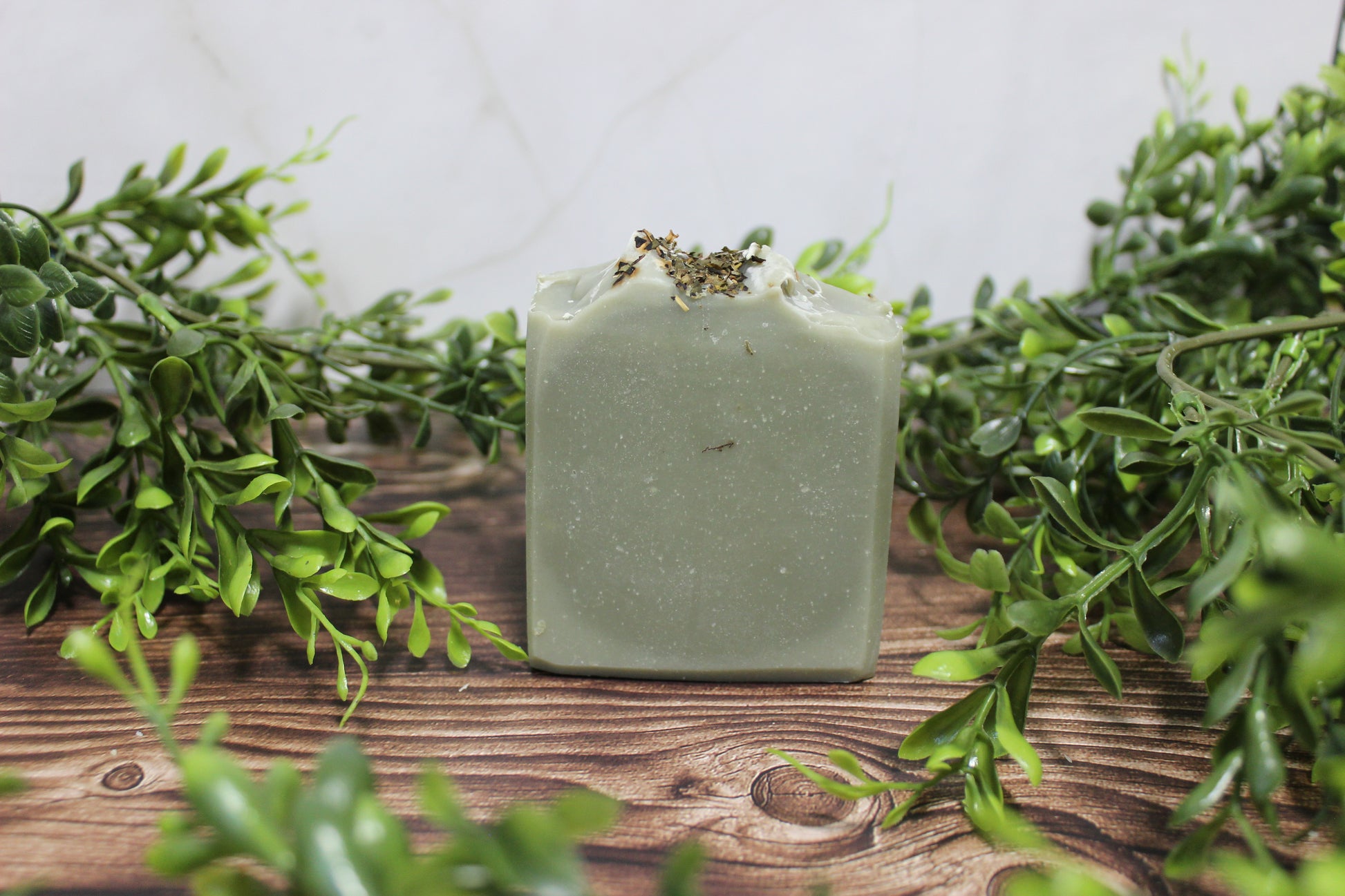 Green soap bar on a wooden surface with green leaves