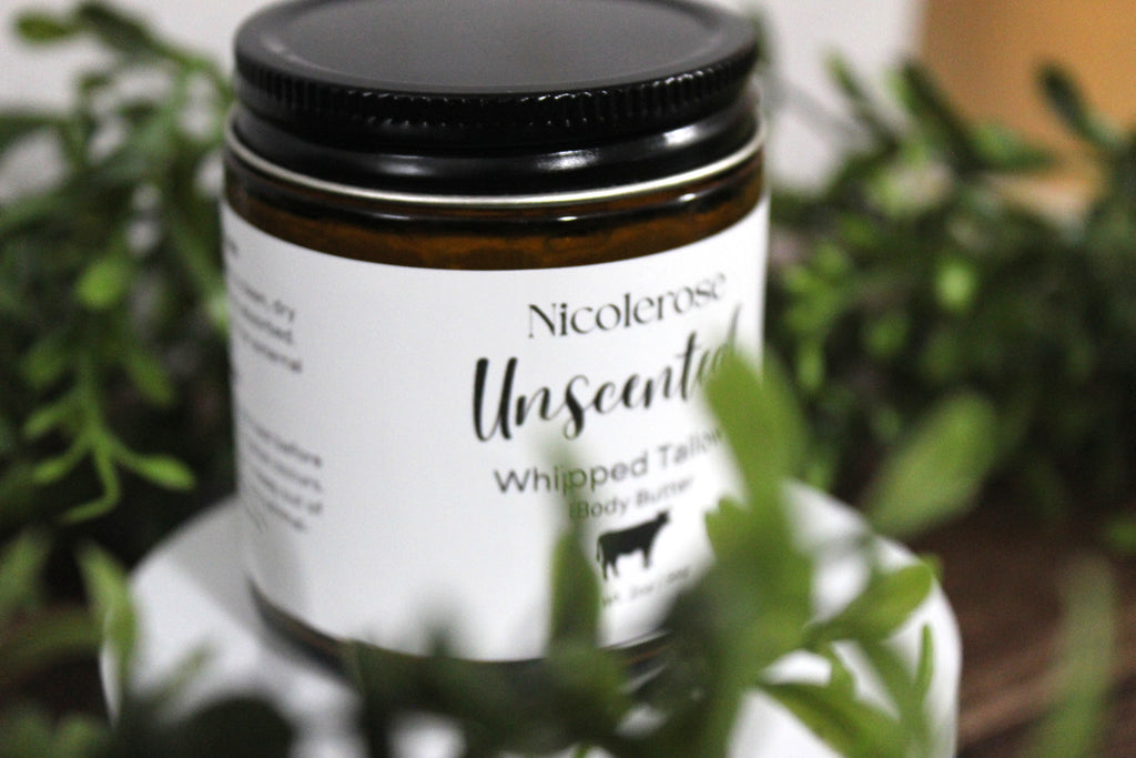 Jar of Nicoleros Unscented Whipped Tallow Balm with greenery in the background