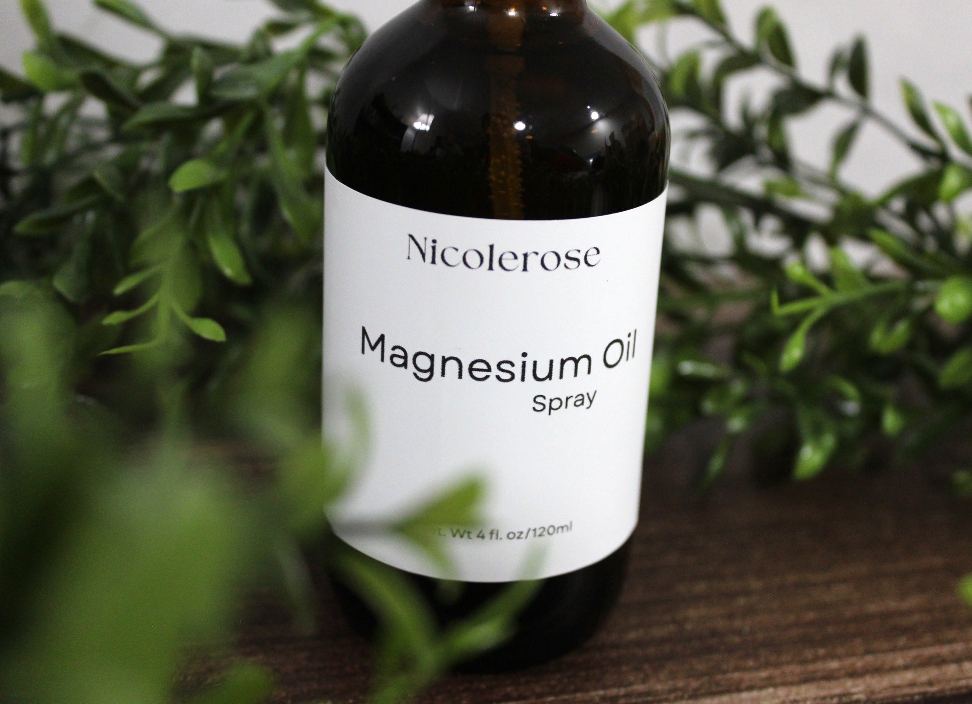 Nicolerose Magnesium Oil Spray bottle with green leaves in the background
