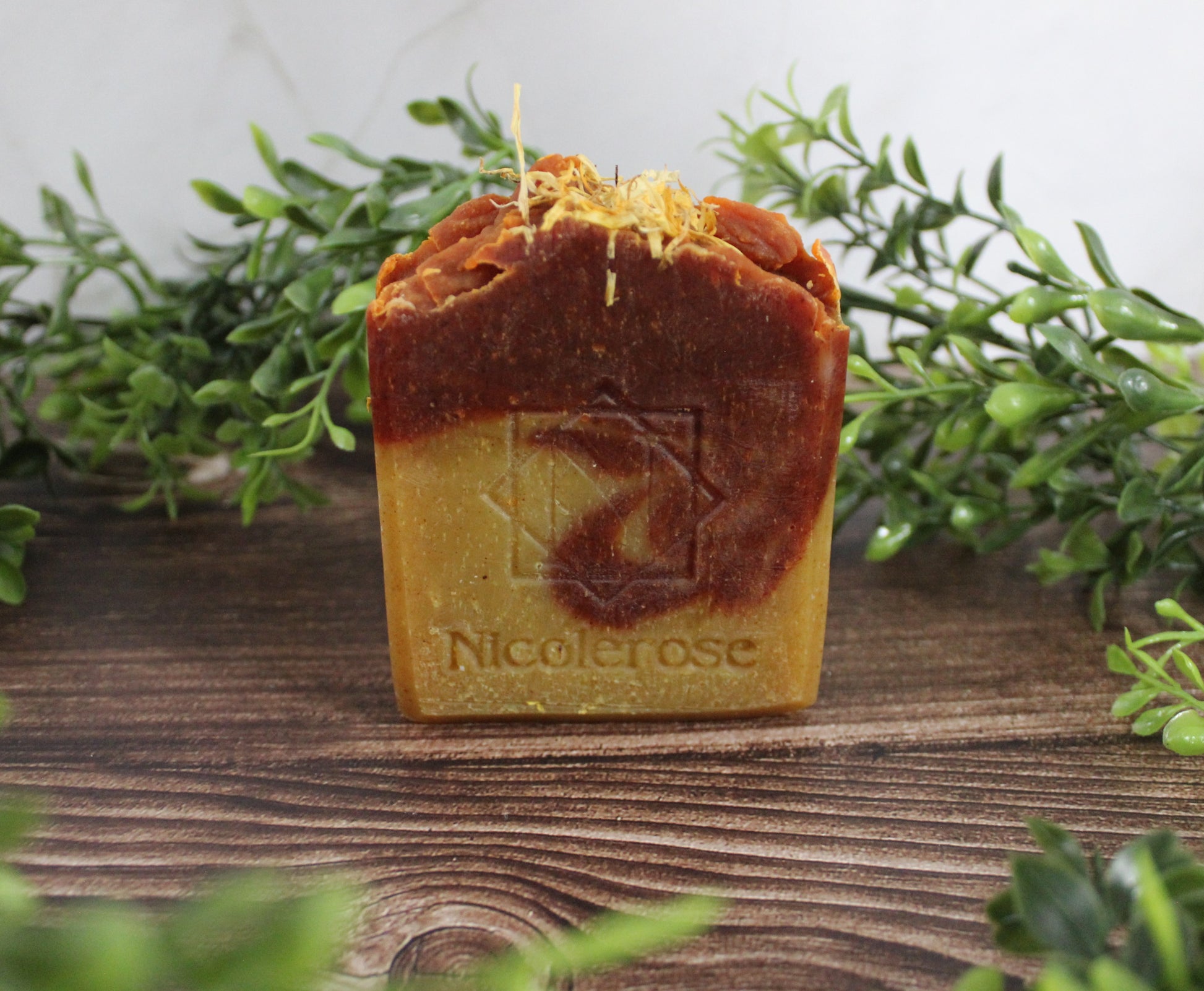 Bar of soap with 'Nicole Rose' branding on a wooden surface with greenery