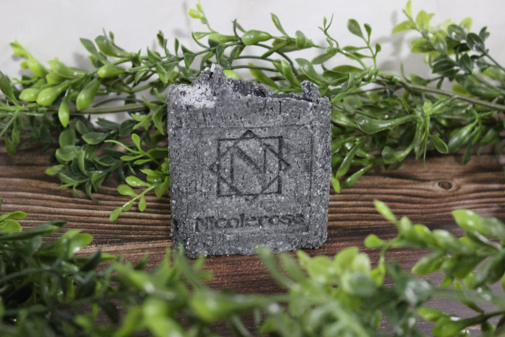 Salt Soap bar with a logo on a wooden surface surrounded by greenery