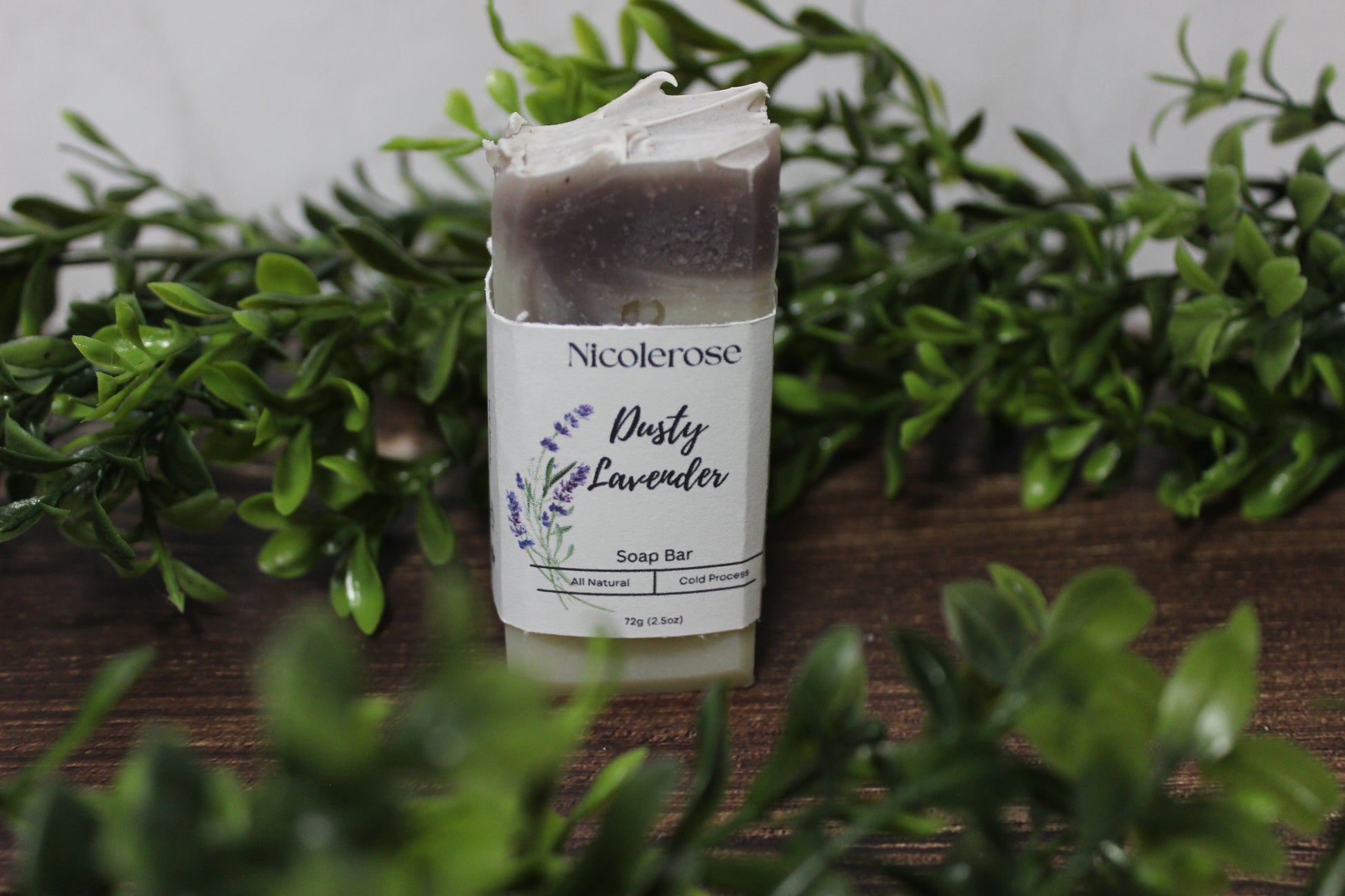 Nicolerose soap bar with 'Dusty Lavender' scent on a wooden surface with greenery.